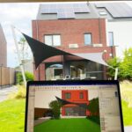 Laptop screen displaying a 3D architectural render of a red brick house with solar panels on the roof, in a sunny backyard with shade sails.