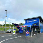 Blue carwash building with a prominent 'Carwash' sign and a small parking area in front.