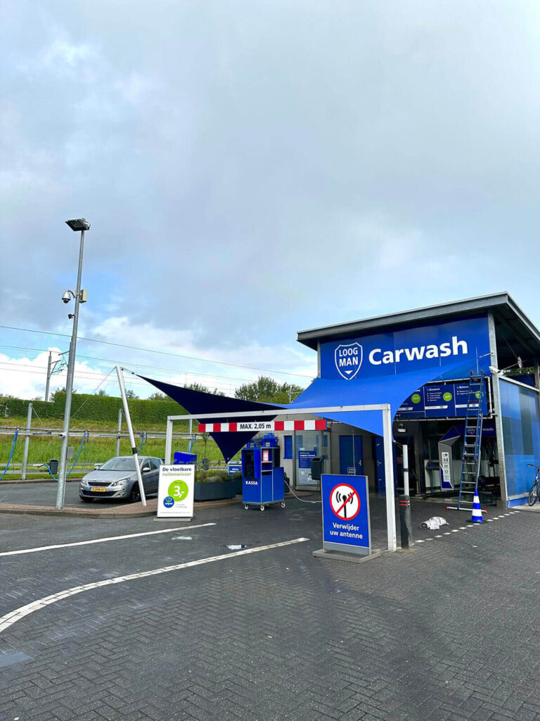 Blue carwash building with a prominent 'Carwash' sign and a small parking area in front.