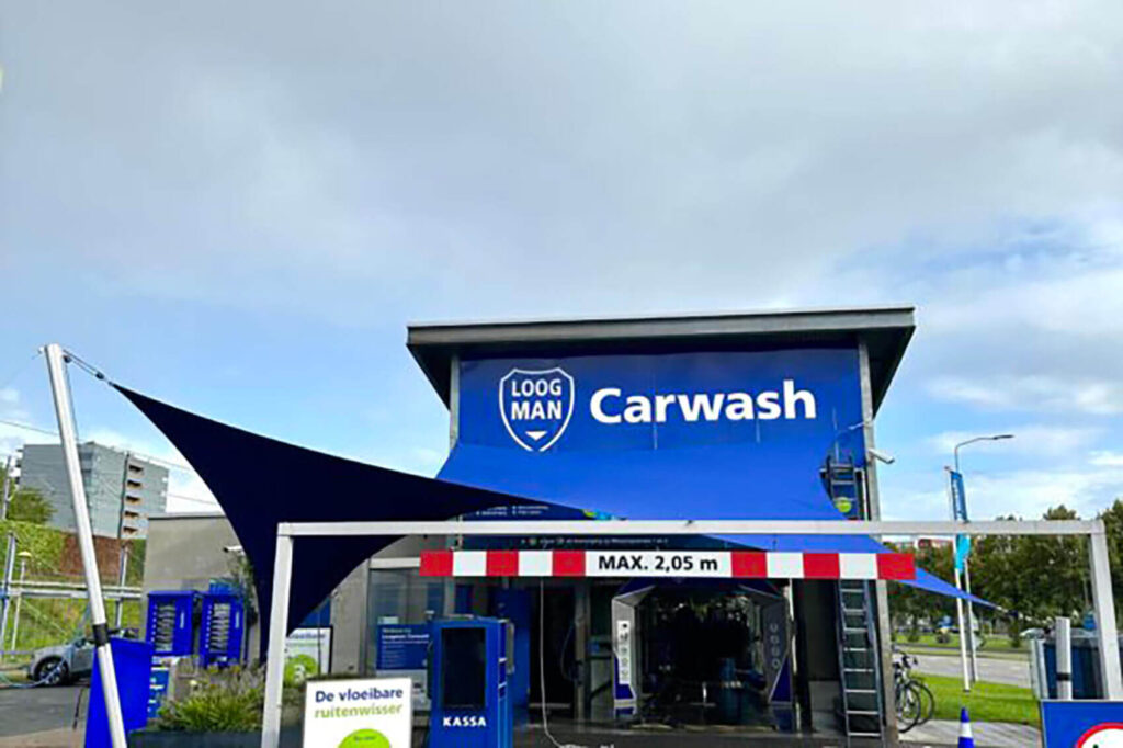Blue carwash building with a curved dark canopy and a large 'Carwash' sign on a blue facade.