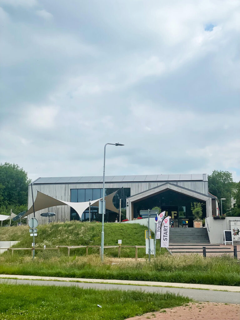 Modern community building with solar panels, shaded outdoor area, and a Start banner by the entrance stairs.